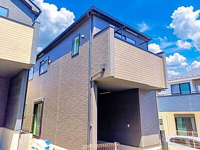 外観：ダークトーンの外壁に木目調のアクセントを効かせた、重厚感と温かみを兼ね備えた外観デザイン。切妻屋根が織りなす陰影も美しく、街並みに映える上質な佇まいです。
