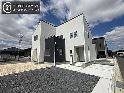 外観：シンプルで現代的なデザインの外観が特徴です。白とグレーのツートンカラーが印象的です。広い駐車スペースも確保されています。開放感のある角地に位置しています。青空に映える外観が魅力的です。