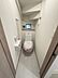 トイレ：シンプルな内装のトイレです。小窓付きで換気や採光が可能です。手すりやペーパーホルダーなど必要な設備が備わっています。壁や床も落ち着いた色合いです。居住空間から近い場所に配置されています。