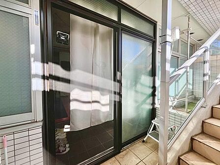 大きなガラス引き戸が印象的な玄関です。明るい光が差し込む開放的な印象を与えます。隣接の階段や屋根付きの通路が便利です。室内へのアクセスがスムーズで外からの目線も配慮された設計になっています。