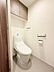 トイレ：清潔感のあるトイレ空間です。手洗い一体型の便器が設置されています。壁面には収納棚があり使い勝手にも配慮されています。温水洗浄機能付きのパネルも備わっています。シンプルで使いやすい設計です。