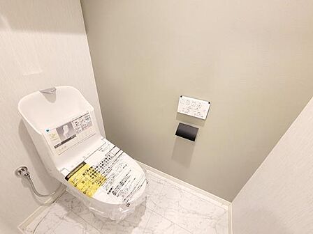 清潔感のある内装が特徴のトイレです。白を基調とした落ち着きのあるデザインとなっています。ゆとりのある空間で使いやすいレイアウトです。床材や壁の色合いが優しい印象を与えます。