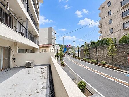広々としたバルコニーから道路を見渡せる現地からの眺望です。周囲はマンションや緑もあり開放感が感じられます。晴れた日は青空が広がり明るい雰囲気が特徴的です。