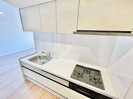 キッチンはシンプルなデザインで全体的に清潔感があります。収納スペースが豊富で整理しやすい仕様です。シンクとコンロの配置も使いやすさに考慮されています。