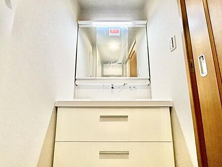 清潔感のある洗面台で収納スペースも充実しています。明るい照明が備わり毎日の身支度も快適です。鏡が広く使いやすさに配慮されています。シンプルなデザインが空間に調和しています。