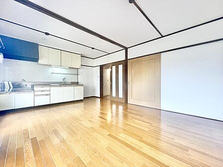 明るいフローリングが広がるリビングです。キッチンが隣接しており使いやすいレイアウトとなっています。大きな扉や収納スペースもしっかり備えています。壁や天井のラインがすっきりした印象を与えます。