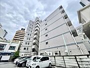 シンプルなデザインの外観が特徴的です。敷地内には複数台分の駐車スペースがあります。周囲には建物が立ち並び都市的な雰囲気を感じられます。建物の階数が多く存在感があります。清潔感のある外壁が印象的です。