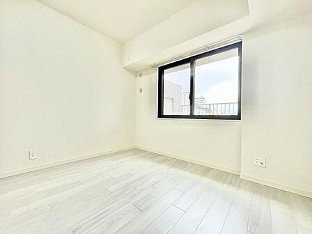 明るい光が差し込む寝室です。シンプルな内装で家具の配置もしやすい空間となっております。窓からは外の景色を楽しめるため開放感があります。床材も明るい色合いで清潔感を感じられます。