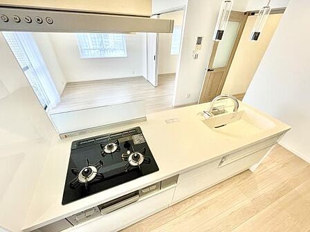 キッチンは明るく開放感のある空間です。ガスコンロが3口あり作業スペースも広く取られています。シンクやコンロ周りがすっきりしており毎日のお手入れもしやすいです。全体的に清潔感の感じられるデザインです。