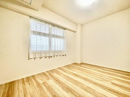 明るい印象の洋室で清潔感が感じられます。床は木目調で落ち着いた雰囲気を演出しています。窓から自然な光が差し込み室内を快適に保ちます。壁や天井もシンプルな仕上がりです。