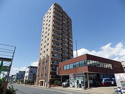 外観：高層マンションの外観が印象的です。近代的な建物で周囲には店舗もあり生活利便性が感じられます。青空に映える明るい外観が特徴です。通り沿いに位置しており建物の存在感があります。