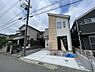 外観：シャープな片流れ屋根と木目調のラインが融合した、意匠性の高いモダンな邸宅。駐車スペースはコンクリート敷きで美しく、お車の出し入れもスムーズです。道行く人の目を引く洗練された佇まいが日常を彩ります。