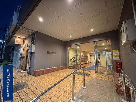 「安心の明るいエントランス」夜間もダウンライトが心地よく灯るアプローチ。スロープと手すりが設置され、ベビーカーや荷物の多い日もスムーズに移動できます。※CG加工により晴天にしています。