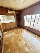 大きな窓からたっぷりと自然光が差し込む洋室です。木目のフローリングが室内に温かみを与えています。天井や壁も木の質感が感じられ落ち着いた雰囲気が特徴です。収納スペースも備えられています。