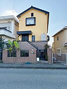洗練されたデザインの外観が特徴的です。黄色い外壁が青空に映えて印象的です。建物全体が落ち着いた雰囲気を醸し出しています。街並みに調和しつつも存在感のあるたたずまいです。