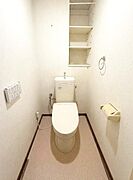 【一部AIによるモノ消し済み】壁面に収納棚が設けられており整理整頓がしやすいトイレです。温水洗浄便座が付いている点も特徴的です。