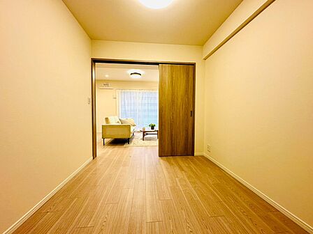 シンプルな洋室と隣接するリビングが見える室内
