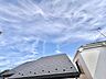外観：青空を背景にした住宅の屋根と外壁の様子