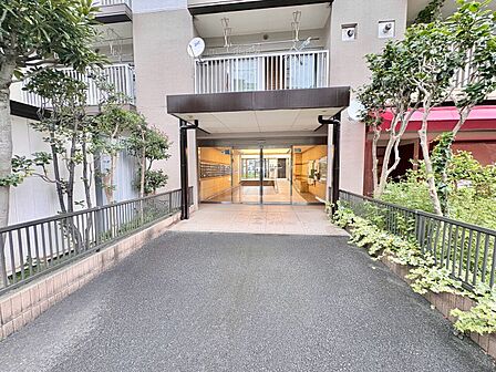 建物のエントランスと周囲の緑地が見える外観写真です