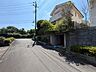 周辺：住宅が建ち並ぶ坂道の様子と周辺の緑が見えます