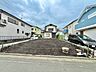 外観：道路に面した更地の敷地周囲に住宅が立ち並ぶ