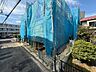 外観：青い養生シートで覆われた建物と前面道路