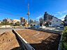 外観：建築前の区画された更地周辺に住宅や建物が見える