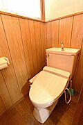 木目調の壁が印象的なトイレです。簡潔なデザインで掃除もしやすい印象です。自然光が差し込む明るい空間となっています。温水洗浄便座が設置されています。