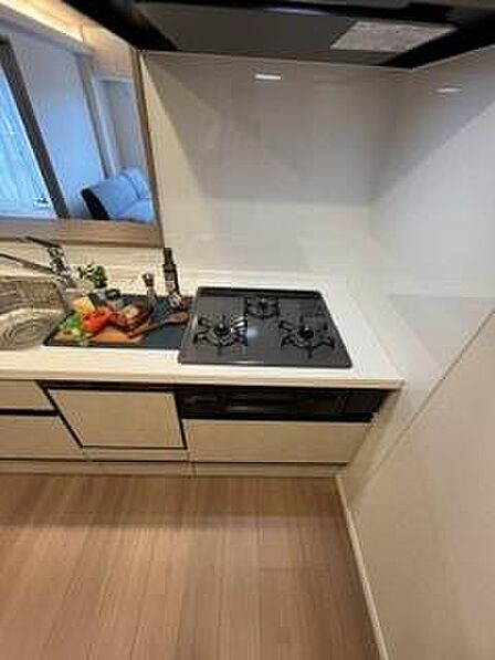 シンプルで清潔感のあるキッチンです。使いやすいガスコンロが設置されています。調理スペースもゆったり確保されています。すっきりとしたデザインが特徴です。換気扇も備わっています。