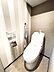 トイレ：ストライプ柄の壁紙が印象的なトイレ空間です。温水洗浄機能を備えた便座が設置されています。タオル掛けやトイレットペーパーホルダーも使いやすい位置に配置されています。