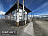 その他：視界が広がる前面道路に面した現地写真です。フェンスで囲まれた敷地が印象的です。青空と建物のコントラストが特徴的な一枚です。開放感ある道路沿いの立地が伝わる写真です。