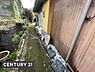 その他：建物横のスペースは様々な用途に活用できる通路です。外壁が木目調で温かみのある印象を与えます。両側の緑や植栽がアクセントになっています。メンテナンスもしやすい配置となっています。
