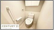 白を基調とした内装で明るく清潔感のあるトイレです。手すりが設置されており使いやすさに配慮されています。収納スペースも確保されておりすっきりとした印象です。スペースがゆったりしています。