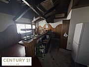 天井の梁が特徴的な内装です。カウンター付きの広々としたスペースが印象的です。木目調の壁面が温かみを感じさせます。冷蔵庫やエアコンも設置されています。窓から入る自然光が室内を明るく演出します。