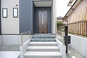 シンプルで落ち着いたデザインの玄関が住まいの印象を引き締めます。段差も低く設計され日々の出入りが快適です。門扉やフェンスが玄関までの導線をしっかりと確保しています。