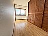 子供部屋：明るい日差しが入る窓が魅力の子供部屋です。木目調のクローゼットがしっかりと収納スペースを確保しています。床はナチュラルなフローリングで清潔感のある印象です。すっきりとしたレイアウトが可能な空間です。