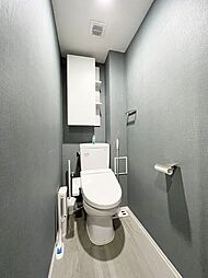 [トイレ] ウォシュレット機能付きのトイレ。ペーパーホルダーやタオル掛けは標準装備しています。また、上部には吊戸棚があるので、トイレットペーパーのストックや清掃道具等を収納するのに便利です。